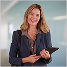 REALTOR® holding a tablet and smiling.